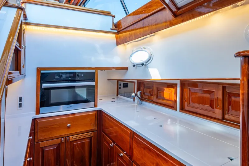Oldielox 2 Yacht Photos Pics Luxurious kitchen interior of 2019 Hinckley T55 MKII Motor Yacht with wood cabinetry and modern appliances.