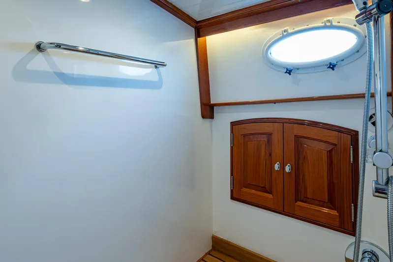 Oldielox 2 Yacht Photos Pics Interior of 2019 Hinckley T55 MKII Motor Yacht bathroom with wooden cabinets and porthole.