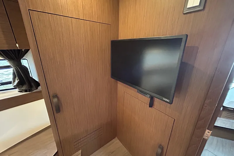  Yacht Photos Pics 2024 Beneteau Antares 11 interior with mounted TV and wooden cabinetry.