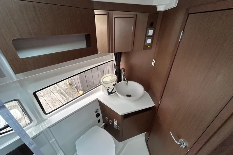  Yacht Photos Pics 2024 Beneteau Antares 11 bathroom with modern sink, wooden cabinetry, and window view.