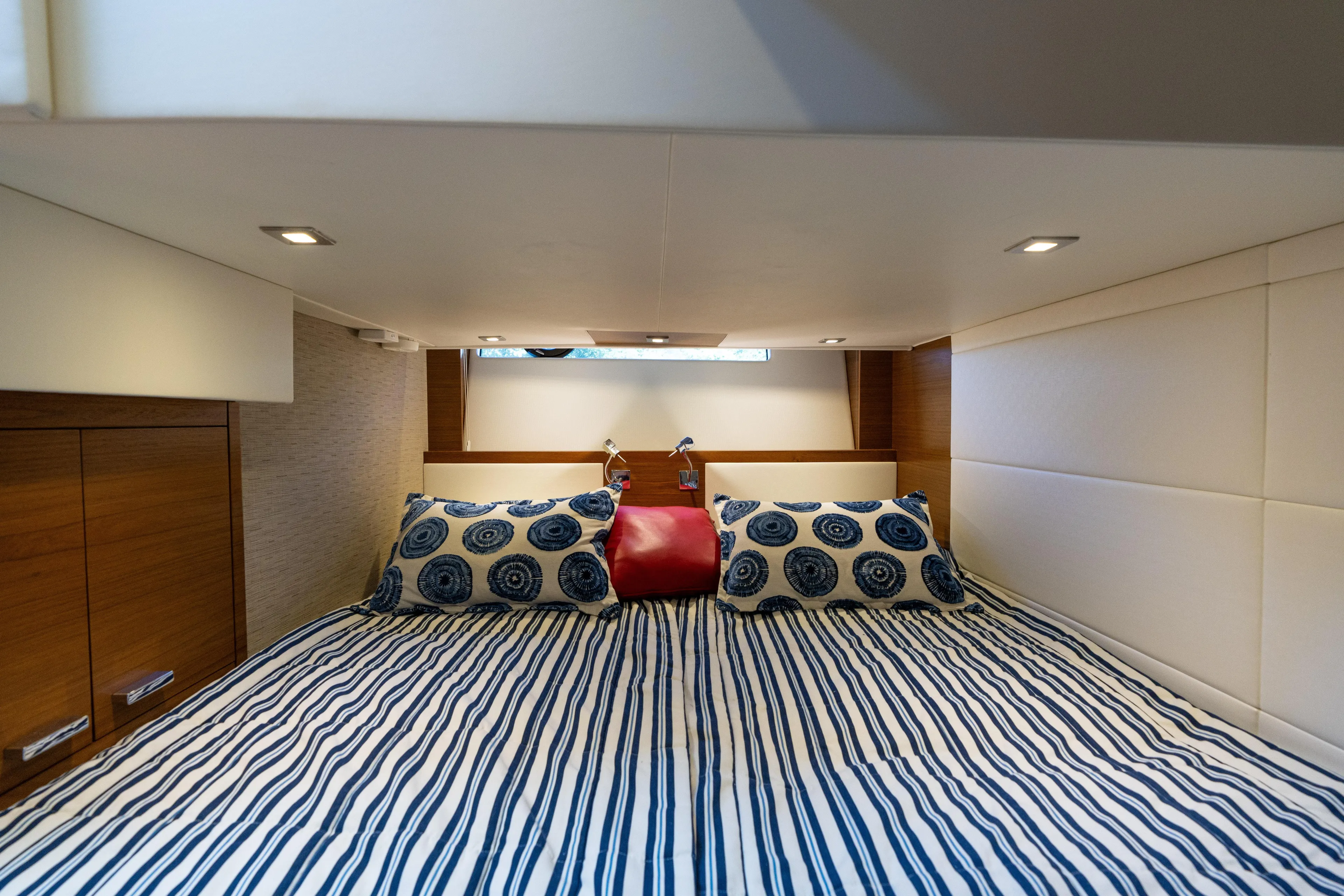 Pyrite Yacht Photos Pics Luxurious bedroom interior of 2015 Tiara Yachts C44 Coupe with striped bedding and modern lighting.