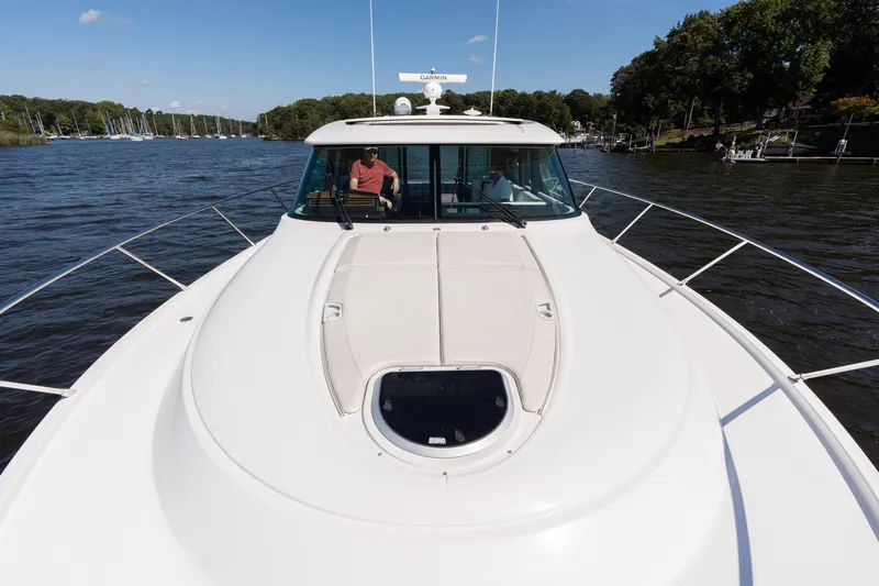 Pyrite Yacht Photos Pics 2015 Tiara Yachts C44 Coupe cruising on a scenic river under a clear blue sky.