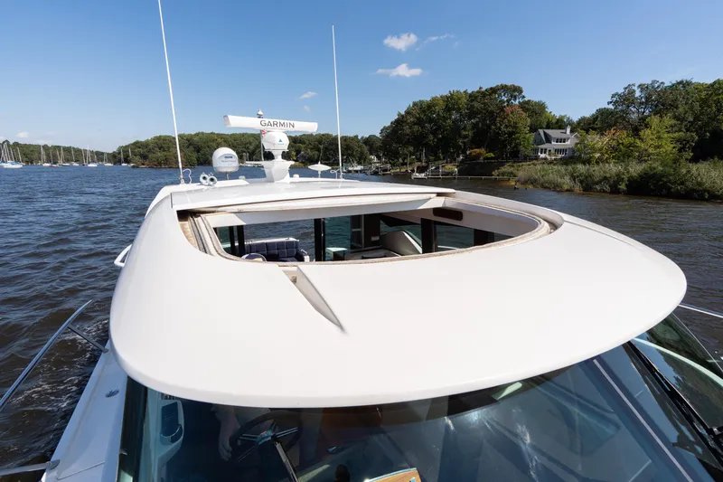 Pyrite Yacht Photos Pics 2015 Tiara Yachts C44 Coupe cruising on a scenic river under a clear blue sky.