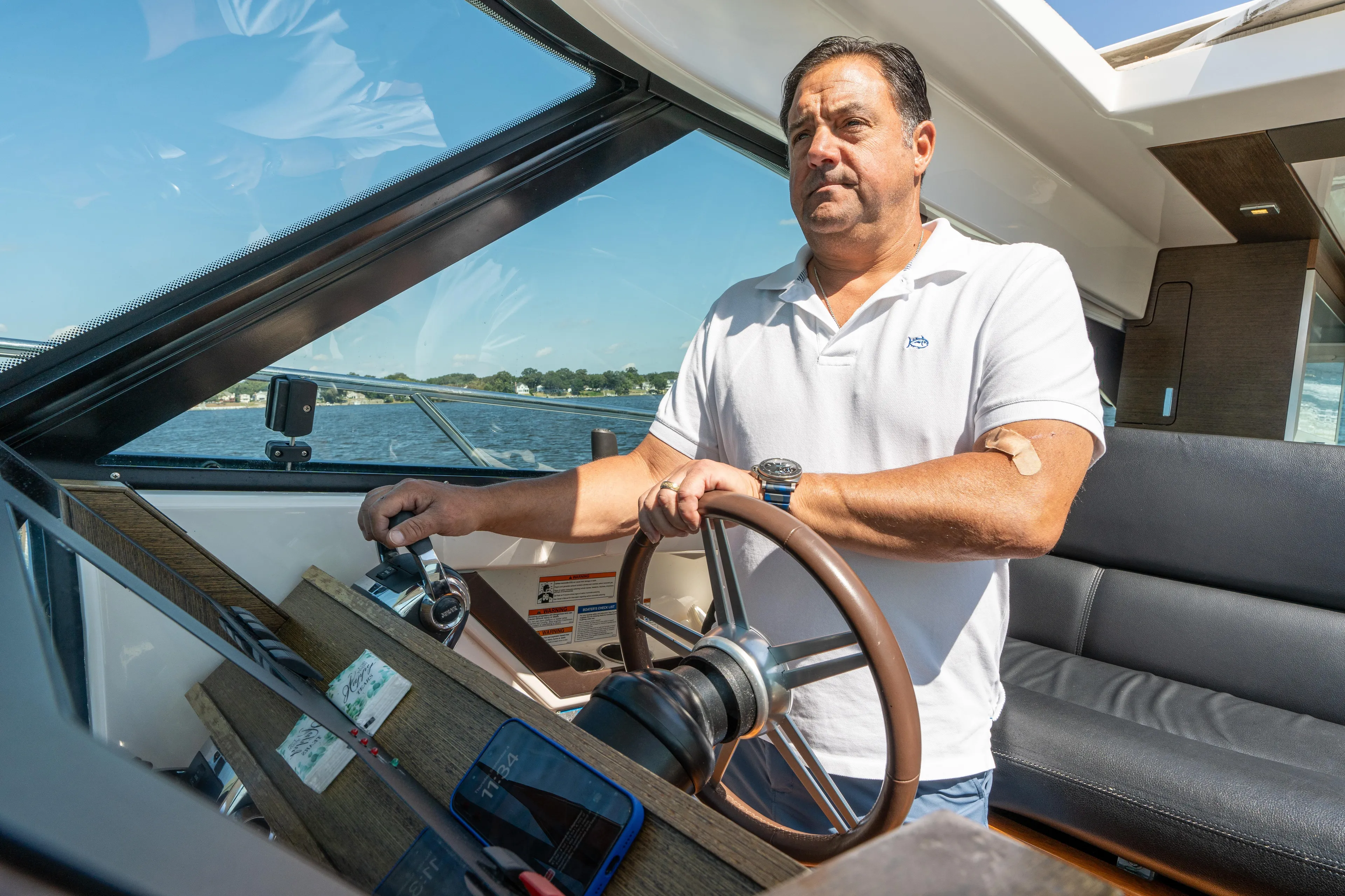 Pyrite Yacht Photos Pics Man steering a 2015 Tiara Yachts C44 Coupe on a sunny day.