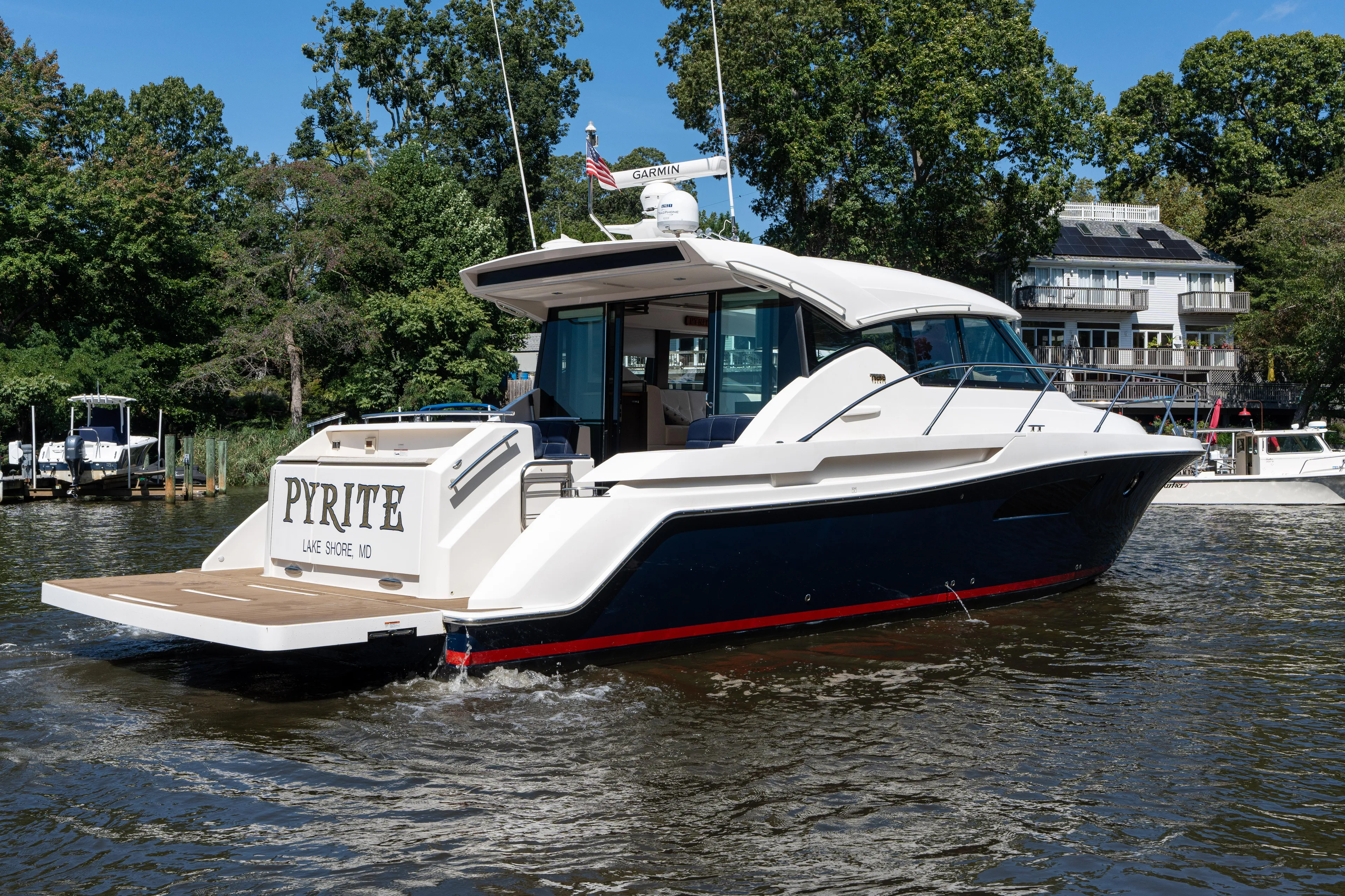 Pyrite Yacht Photos Pics 2015 Tiara Yachts C44 Coupe on water, rear view, docked near trees and buildings.