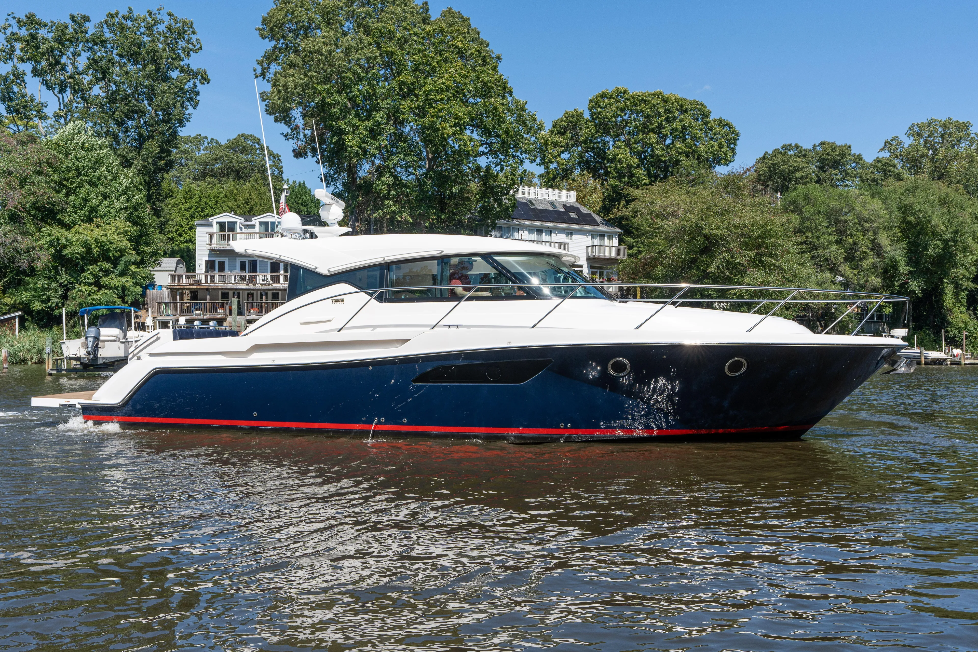 Pyrite Yacht Photos Pics 2015 Tiara Yachts C44 Coupe cruising on a scenic river with lush greenery.