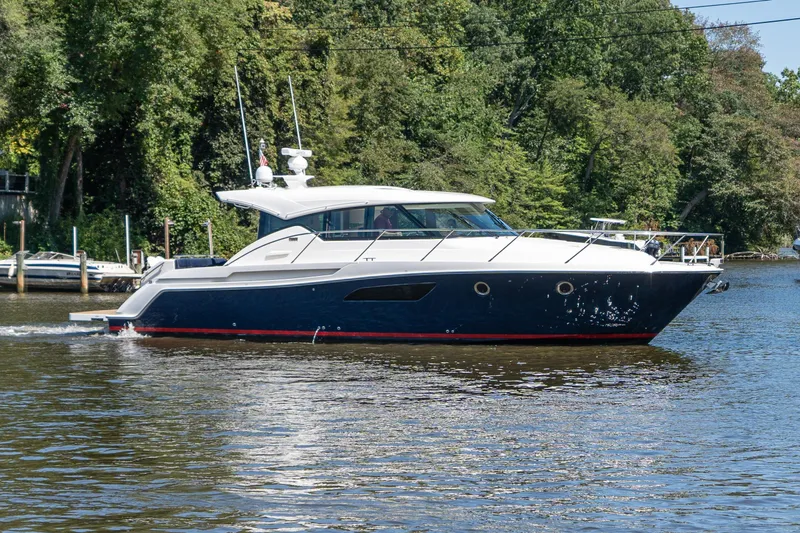 Pyrite Yacht Photos Pics 2015 Tiara Yachts C44 Coupe cruising on a scenic river with lush greenery.
