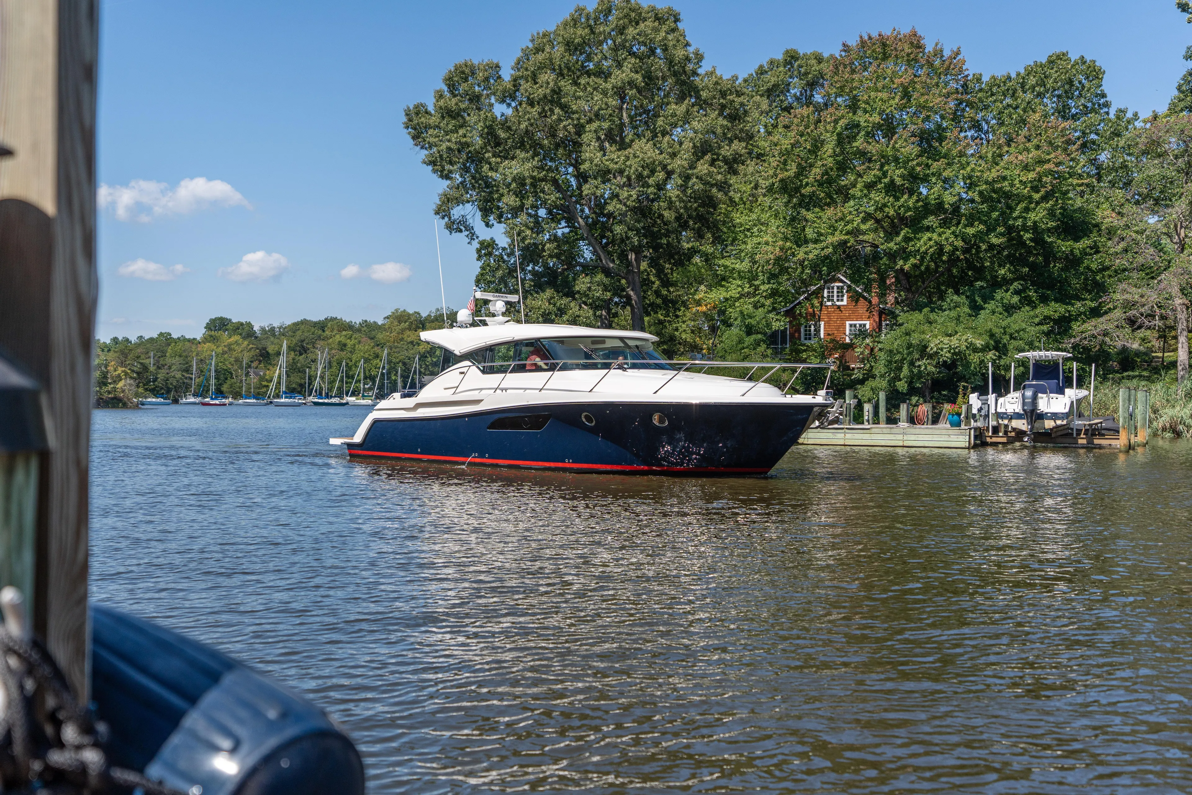 Pyrite Yacht Photos Pics 2015 Tiara Yachts C44 Coupe cruising on a scenic river with lush greenery.