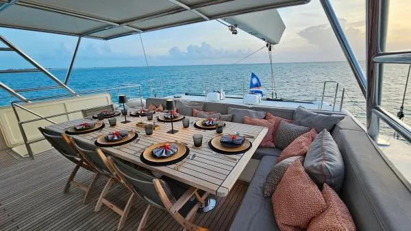 Little Giant Yacht Photos Pics Luxurious Sunreef 88 DD yacht deck with elegant dining setup, ocean view, and comfortable seating.