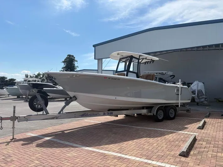  Yacht Photos Pics 2022 SeaHunter 275 ULTRA boat on trailer in parking lot under blue sky.