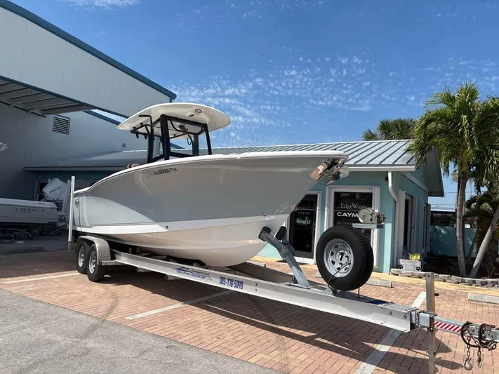  Yacht Photos Pics 2022 SeaHunter 275 ULTRA boat on trailer, parked near a building with palm trees.