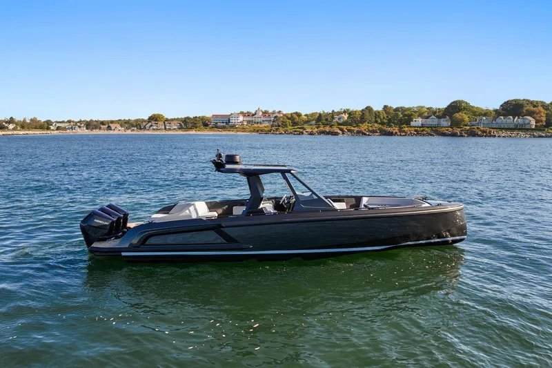  Yacht Photos Pics 2024 Vanquish Yachts 40 on serene water with scenic shoreline background.