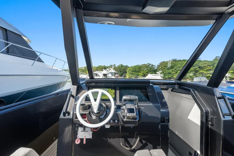  Yacht Photos Pics 2024 Vanquish Yachts 40 helm with modern controls and steering wheel, docked near other boats.
