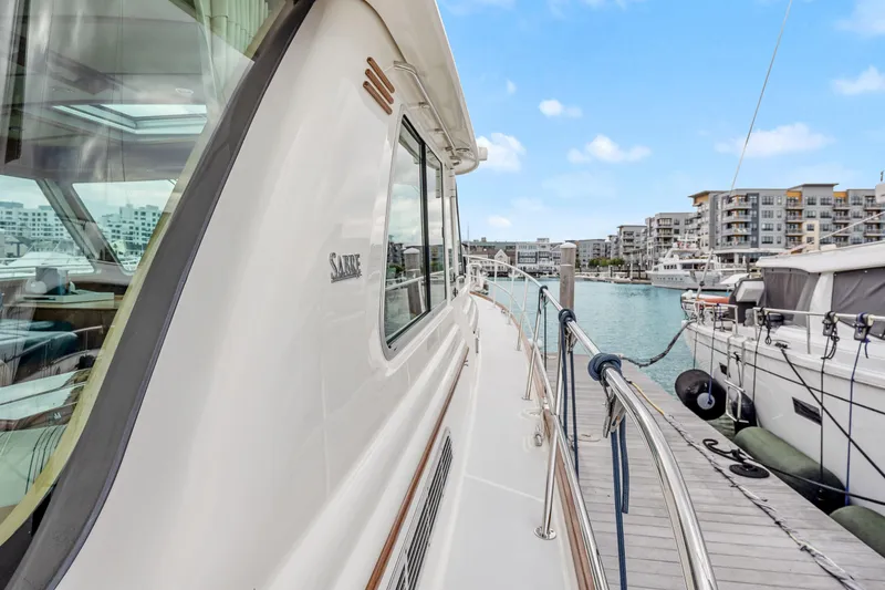 Second Rodeo Yacht Photos Pics 2018 Sabre 48 Salon Express yacht docked at a marina with modern buildings.