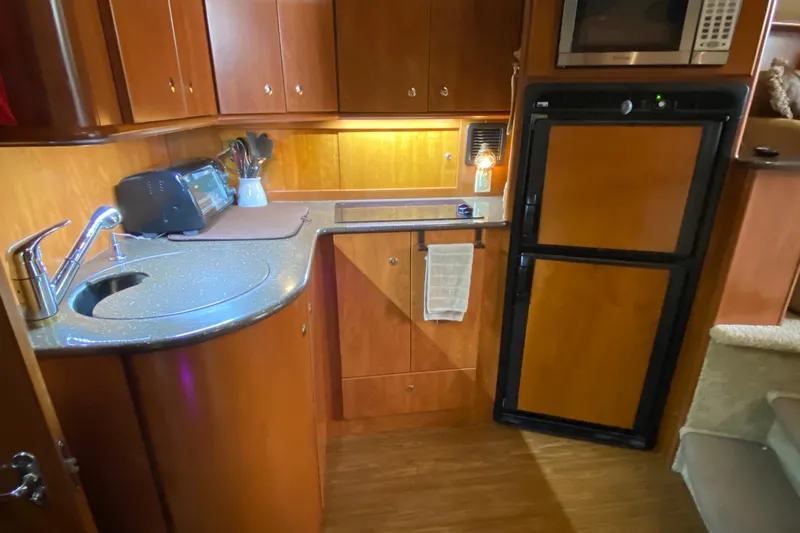 Carousel Yacht Photos Pics 2007 Silverton 36 Convertible yacht kitchen with wood cabinetry, sink, and appliances.