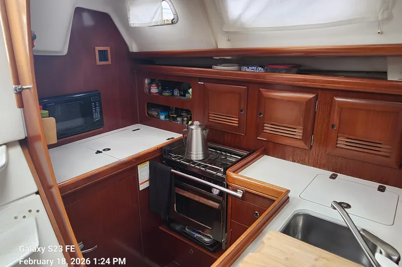 Little Su Yacht Photos Pics Galley of 2005 Beneteau Oceanis Clipper 393 with stove, microwave, and wooden cabinetry.