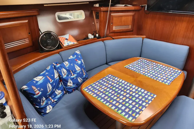 Little Su Yacht Photos Pics Cozy interior of 2005 Beneteau Oceanis Clipper 393 with nautical-themed cushions and wooden table.