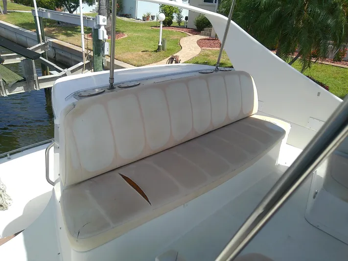 Cash Flow Yacht Photos Pics 2005 Carver 36 Mariner boat seating with visible wear, docked near a landscaped area.