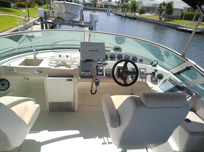 Cash Flow Yacht Photos Pics 2005 Carver 36 Mariner cockpit with steering wheel, navigation equipment, and seating by a canal.