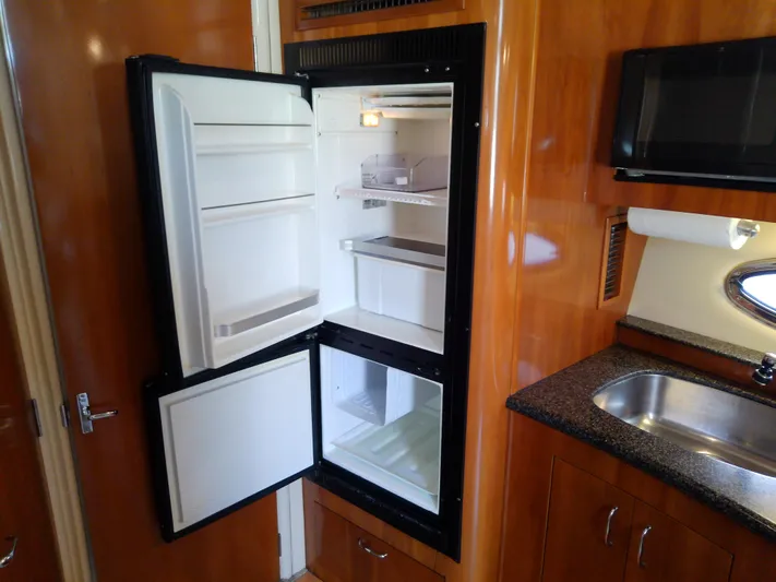 Cash Flow Yacht Photos Pics Open refrigerator in 2005 Carver 36 Mariner yacht kitchen, with wooden cabinetry and stainless steel sink.