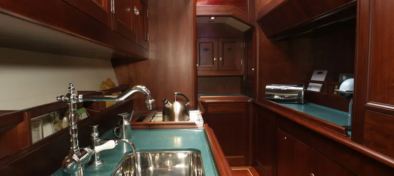 Aldebaran Yacht Photos Pics Luxurious kitchen area in a 2003 JFA Yachts Custom 70, featuring polished wood cabinetry and modern appliances.