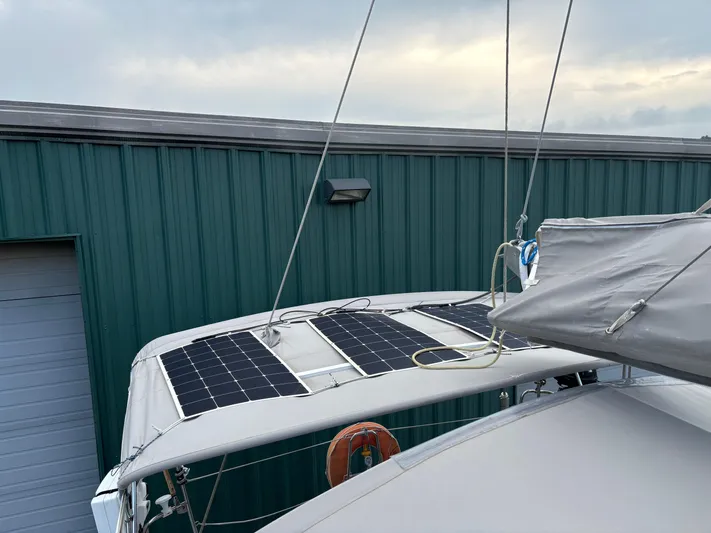 Nemo Yacht Photos Pics Grand Soleil 47 (2015) sailboat with solar panels, docked near a green metal building.