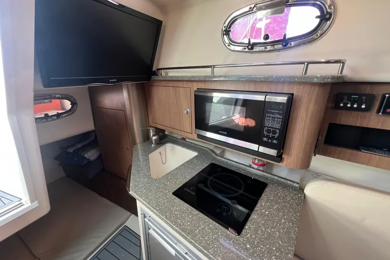  Yacht Photos Pics 2015 Boston Whaler 285 Conquest interior with kitchenette, microwave, and TV.