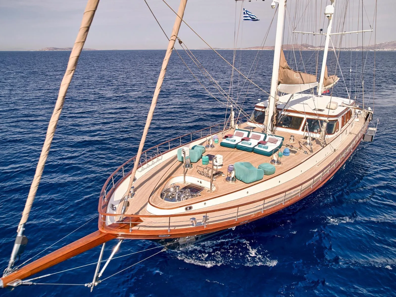 Luxurious custom yacht sailing on clear blue sea, featuring spacious deck with seating, 2009 model.