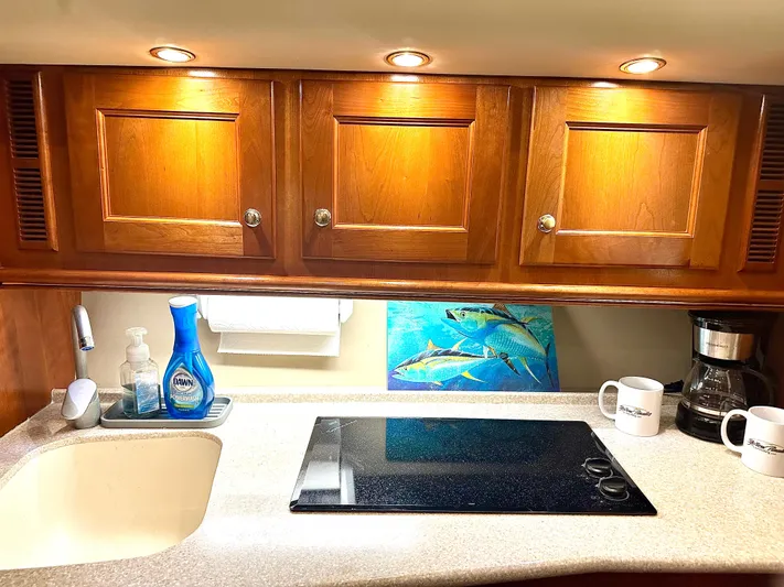  Yacht Photos Pics 2006 Rampage 38 Express kitchen with wooden cabinets, sink, stovetop, and coffee maker.