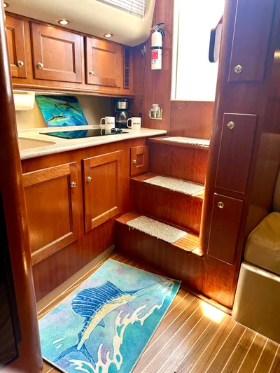  Yacht Photos Pics 2006 Rampage 38 Express yacht interior with wooden cabinets and stairs, featuring a nautical-themed rug.