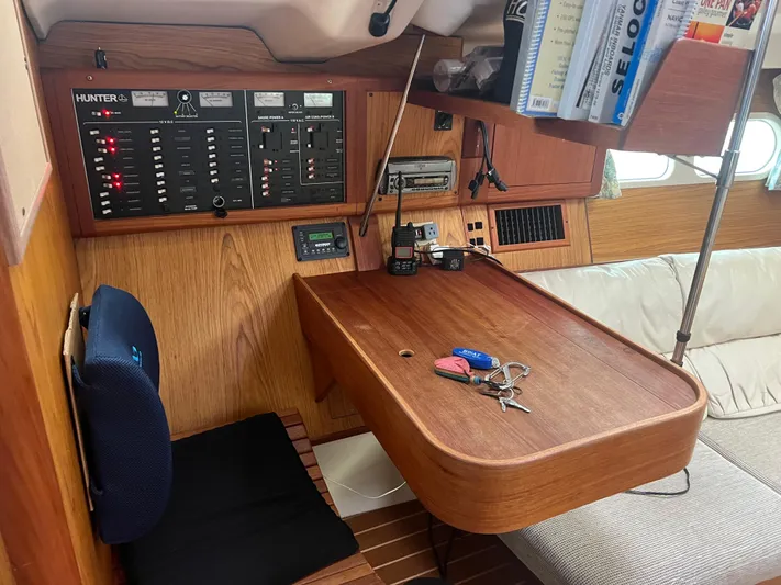 "helluva" Yacht Photos Pics Navigation station in a 2000 Hunter 410 sailboat with control panel and seating area.