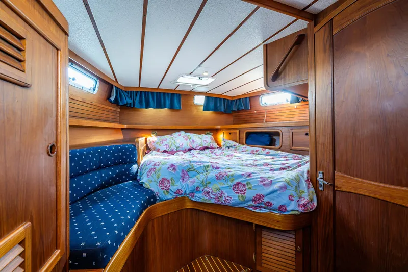 Emeritus Yacht Photos Pics Cozy cabin interior of 2000 Nauticat 35 Pilot House with floral bedding and wood paneling.
