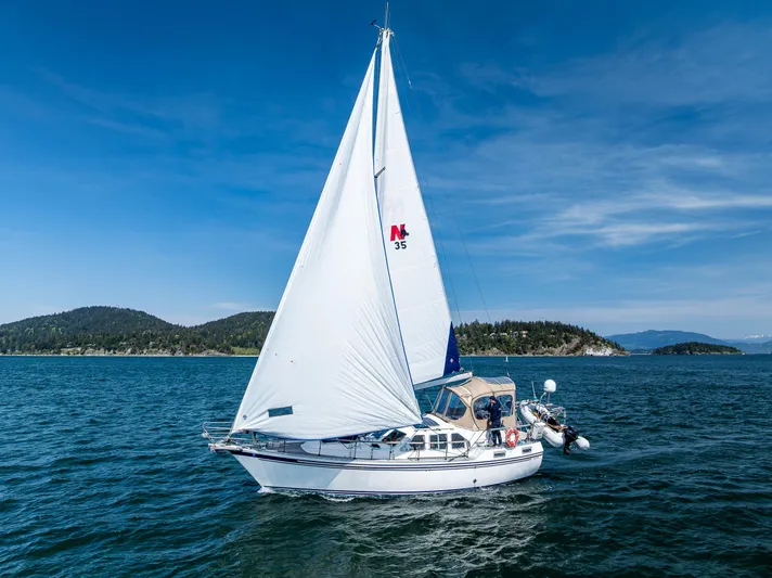 Emeritus Yacht Photos Pics Sailing yacht Nauticat 35 Pilot House 2000 on open water under clear blue sky.