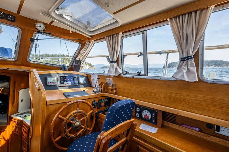Emeritus Yacht Photos Pics Pilot house interior of 2000 Nauticat 35, featuring wooden helm and ocean view.