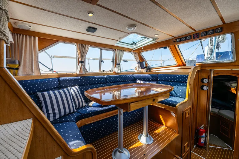 Emeritus Yacht Photos Pics Nauticat 35 Pilot House 2000 interior with wooden table, blue seating, and large windows.