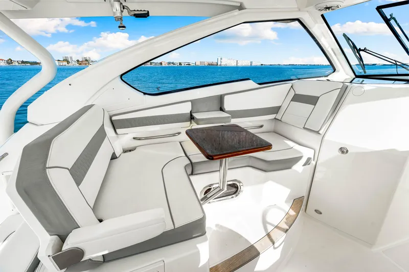 Conspirasea Yacht Photos Pics 2021 Pursuit DC 365 Dual Console interior with seating and table, overlooking blue ocean.