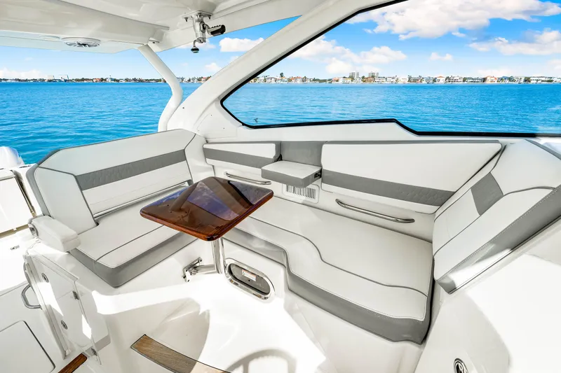 Conspirasea Yacht Photos Pics 2021 Pursuit DC 365 Dual Console interior with seating and table, overlooking blue water.