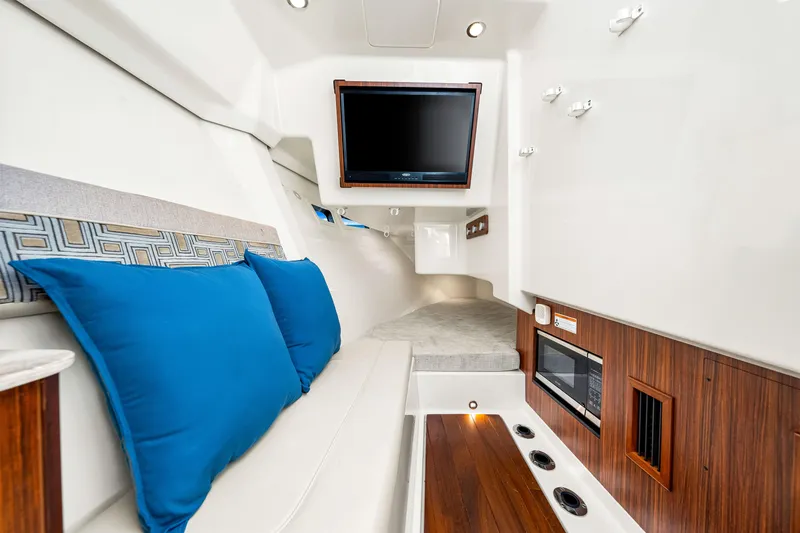 Conspirasea Yacht Photos Pics 2021 Pursuit DC 365 Dual Console interior with TV, blue cushions, and wood accents.
