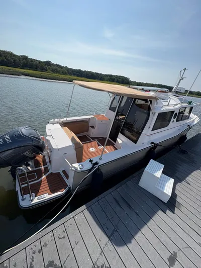  Yacht Photos Pics 2023 Ranger Tugs R-27 boat docked, featuring a canopy and outboard motor.
