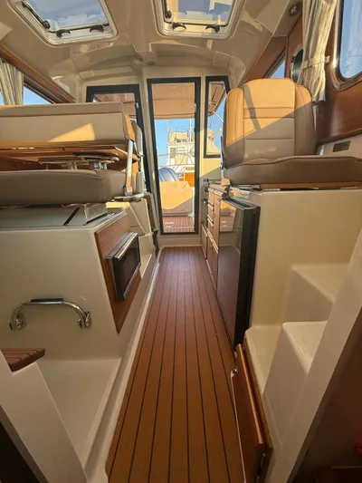  Yacht Photos Pics Interior of 2023 Ranger Tugs R-27 boat, featuring wood flooring and leather seating.