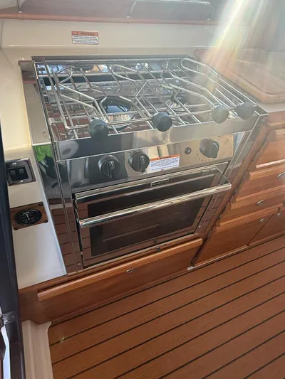  Yacht Photos Pics 2023 Ranger Tugs R-27 boat kitchen with stainless steel stove and wooden cabinetry.