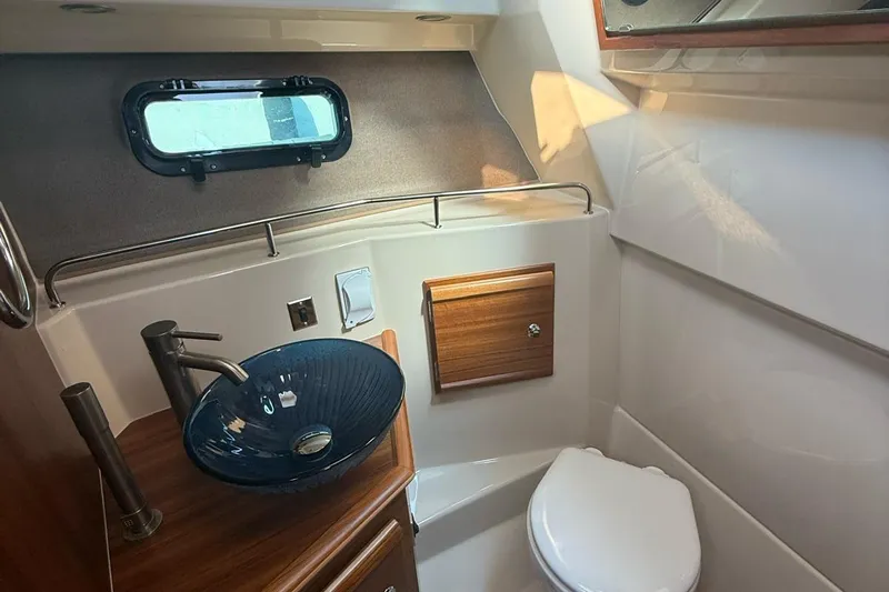 Yacht Photos Pics 2023 Ranger Tugs R-27 bathroom with modern sink, toilet, and porthole window.