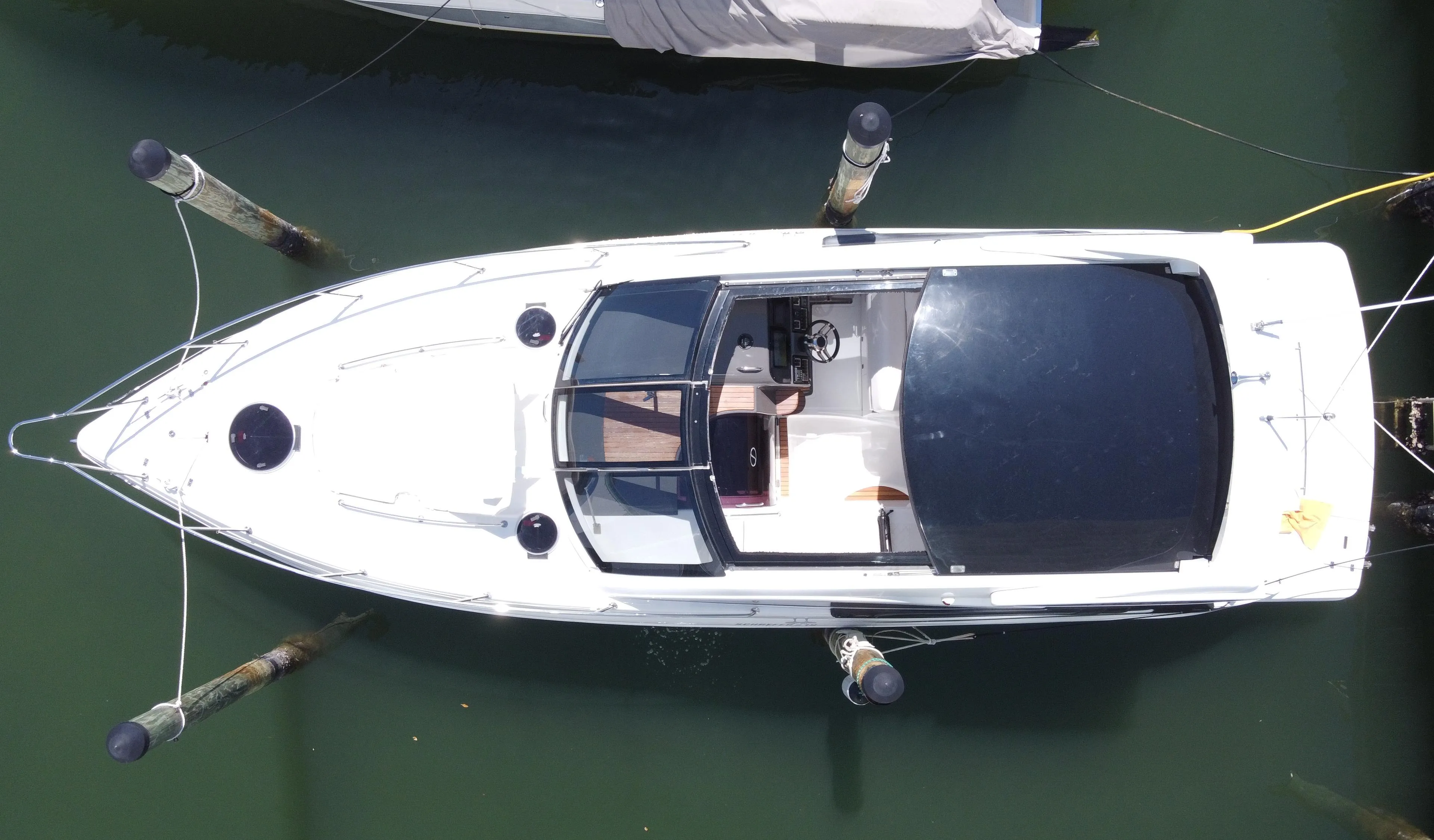 2023 Schaefer 375 HT boat docked, aerial view, sleek design, white hull, black canopy.