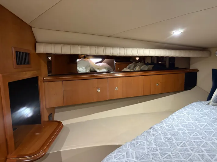 White Lightning Yacht Photos Pics Interior cabin of 2003 Cruisers Yachts 4270 Express, featuring wood cabinetry and cozy bedding.