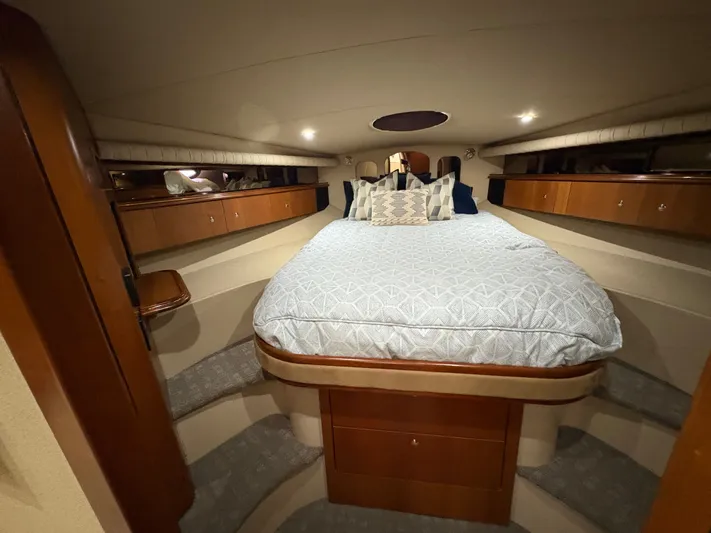 White Lightning Yacht Photos Pics Luxurious cabin interior of 2003 Cruisers Yachts 4270 Express with cozy bed and wooden cabinetry.