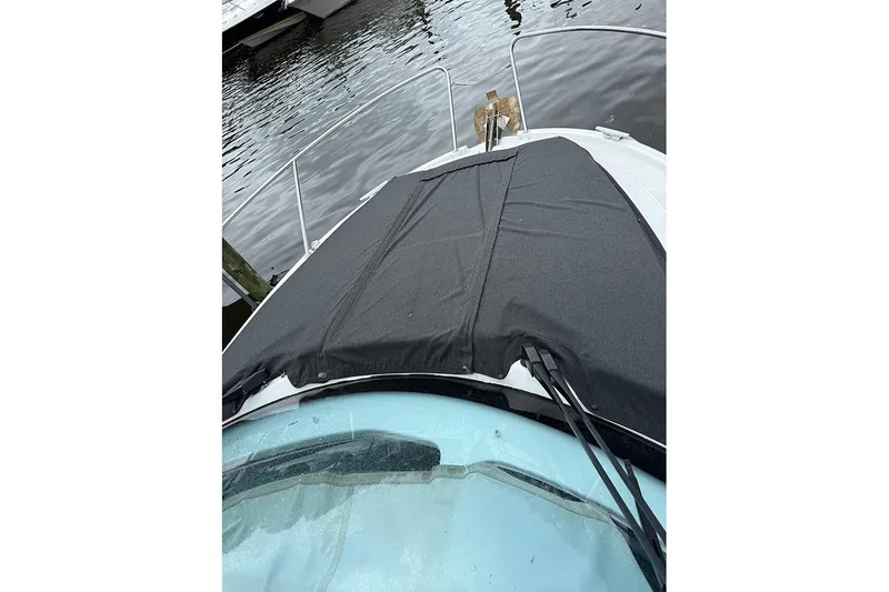  Yacht Photos Pics 2023 Beneteau Antares 9 boat with black cover on deck, docked by water.