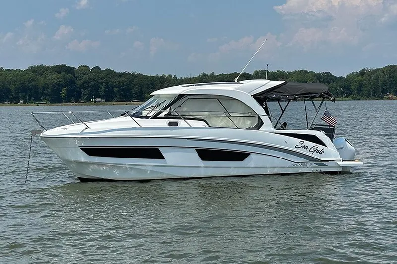  Yacht Photos Pics 2023 Beneteau Antares 9 boat on calm water, side view, with trees in the background.