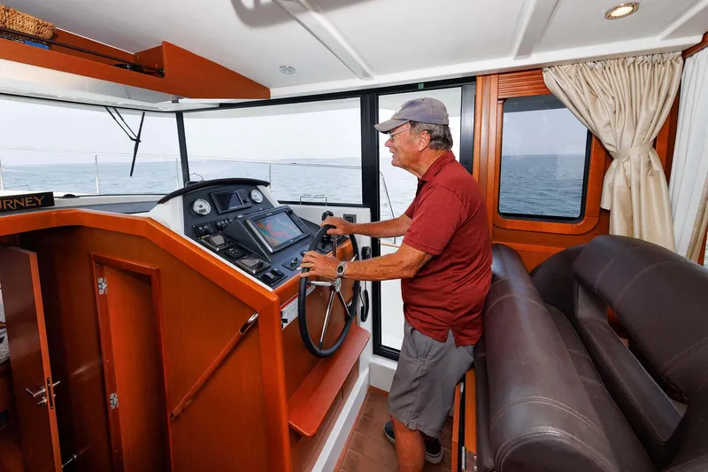 Gotali Yacht Photos Pics Man steering 2016 Beneteau Swift Trawler 44 in cabin, ocean view through windows.