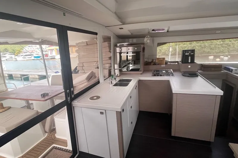 Honu Kai Yacht Photos Pics Modern kitchen interior of 2023 Fountaine Pajot Catamaran Astrea 42 with marina view.