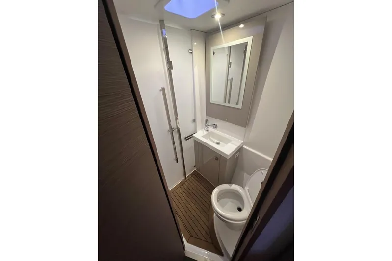 Honu Kai Yacht Photos Pics Modern bathroom in 2023 Fountaine Pajot Catamaran Astrea 42 with sleek fixtures and wooden flooring.